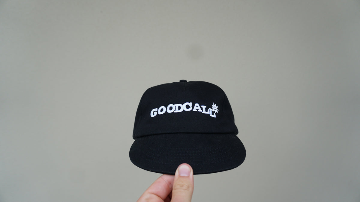 Front view of the black GOODCALL hat with white branding