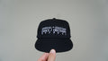 Front view of the black Discovery hat with white Dance / Discovery detailing
