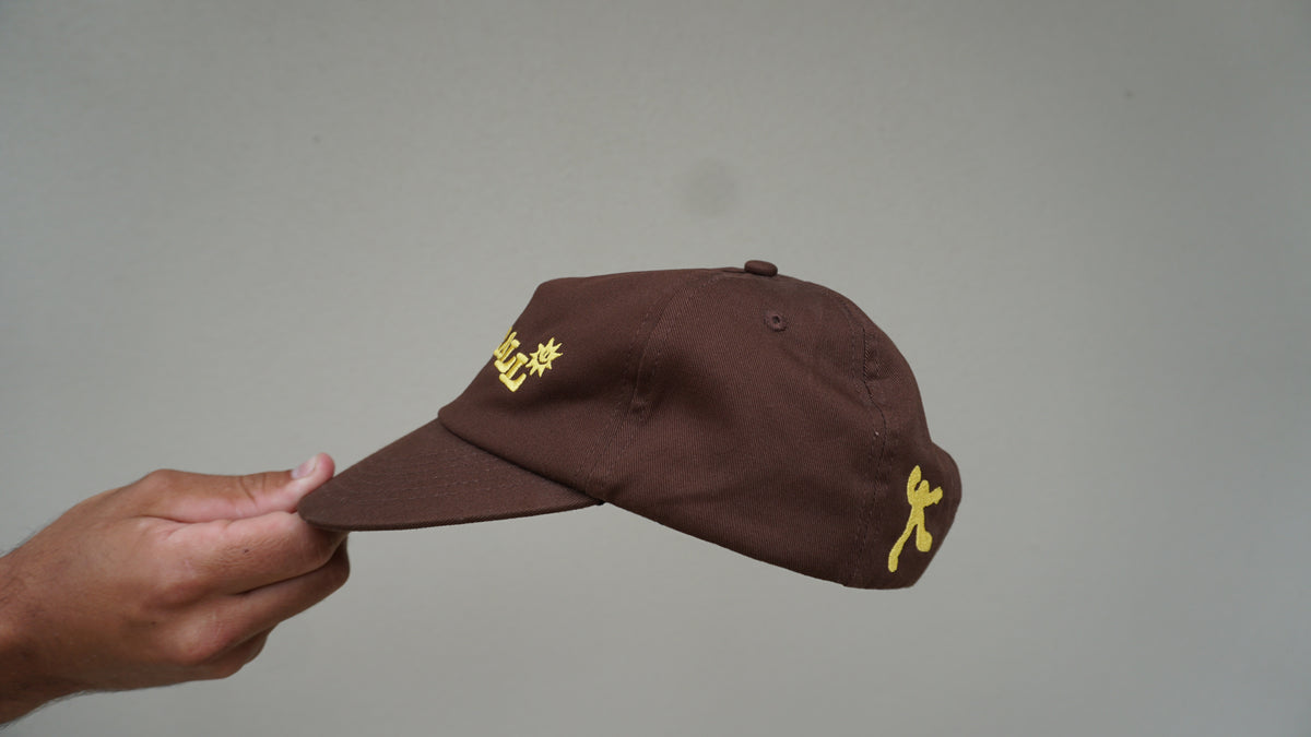 Side view of the brown GOODCALL hat with yellow detailing