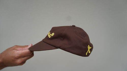 Side view of the brown GOODCALL hat with yellow detailing