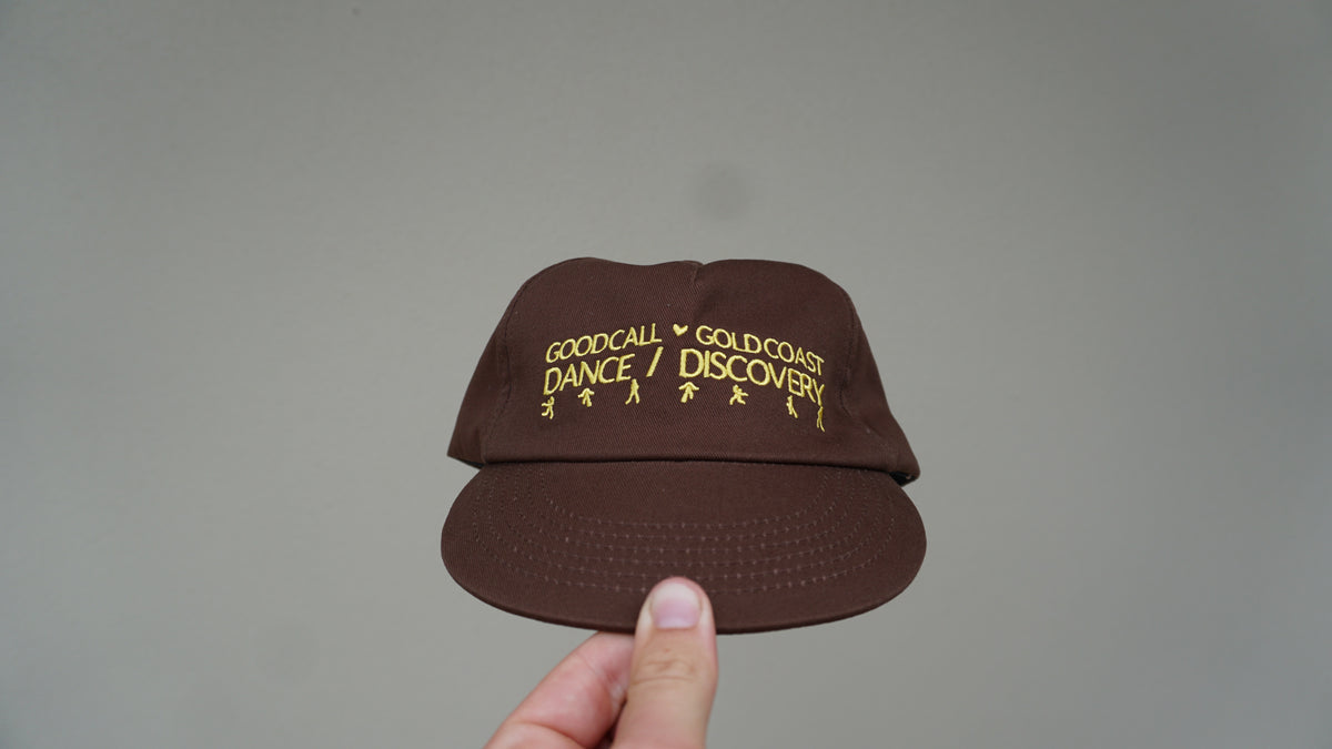 Front view of the brown Discovery hat with yellow lettering and detailing